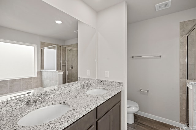 bathroom featuring toilet, vanity, hardwood / wood-style floors, and a shower with door