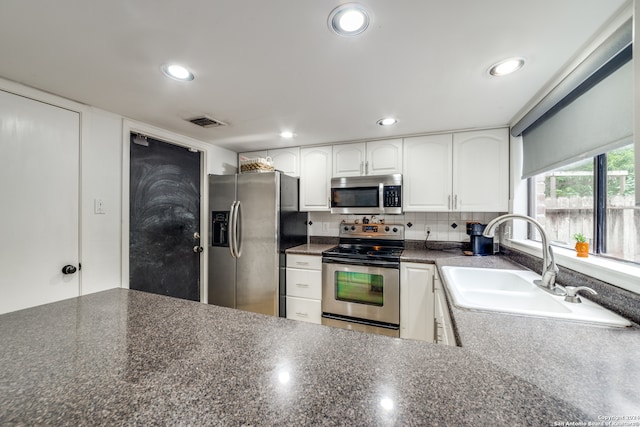 kitchen featuring stainless steel appliances, white cabinetry, sink, and tasteful backsplash