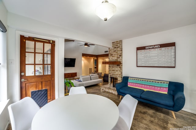 dining area with ceiling fan and a brick fireplace