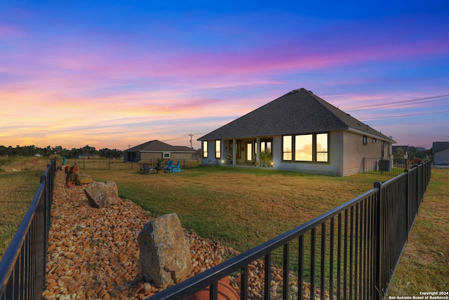 back house at dusk featuring a yard