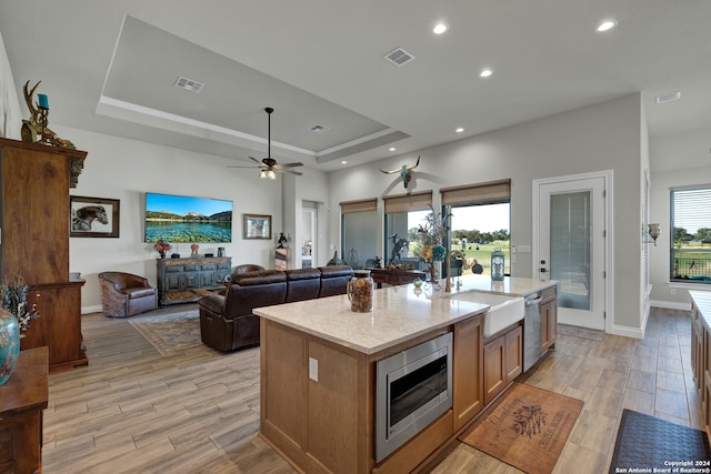 kitchen featuring sink, stainless steel appliances, light hardwood / wood-style floors, and a kitchen island with sink