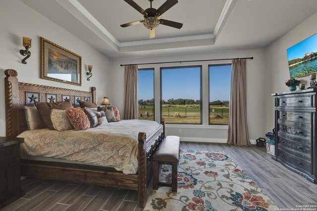 bedroom with ornamental molding, hardwood / wood-style floors, ceiling fan, and a raised ceiling