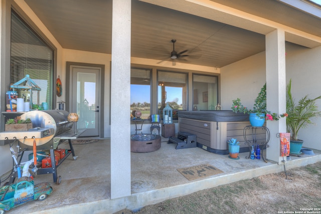 view of patio featuring ceiling fan, an outdoor fire pit, and a hot tub