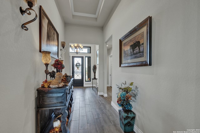 foyer entrance featuring wood-type flooring, a chandelier, and a raised ceiling