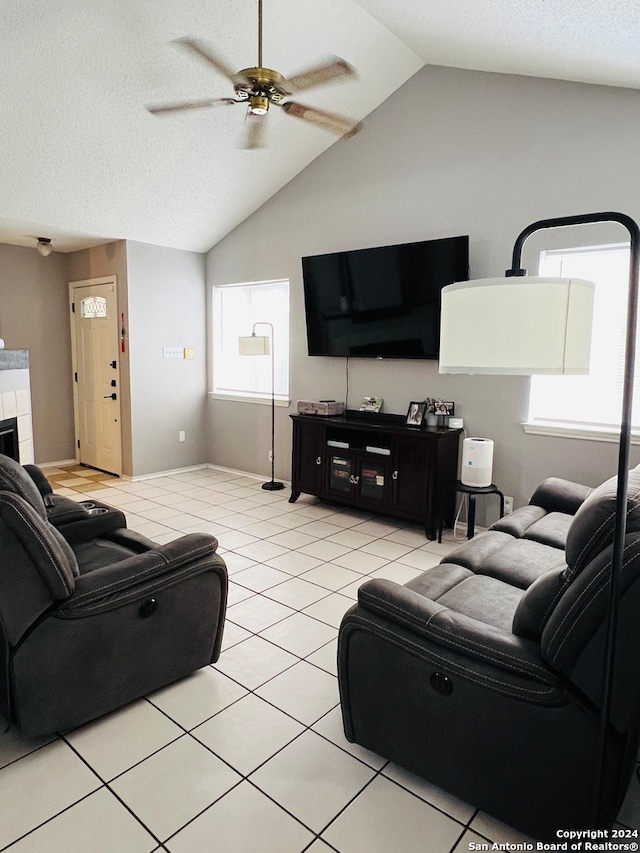 tiled living room featuring lofted ceiling, a textured ceiling, ceiling fan, and a fireplace