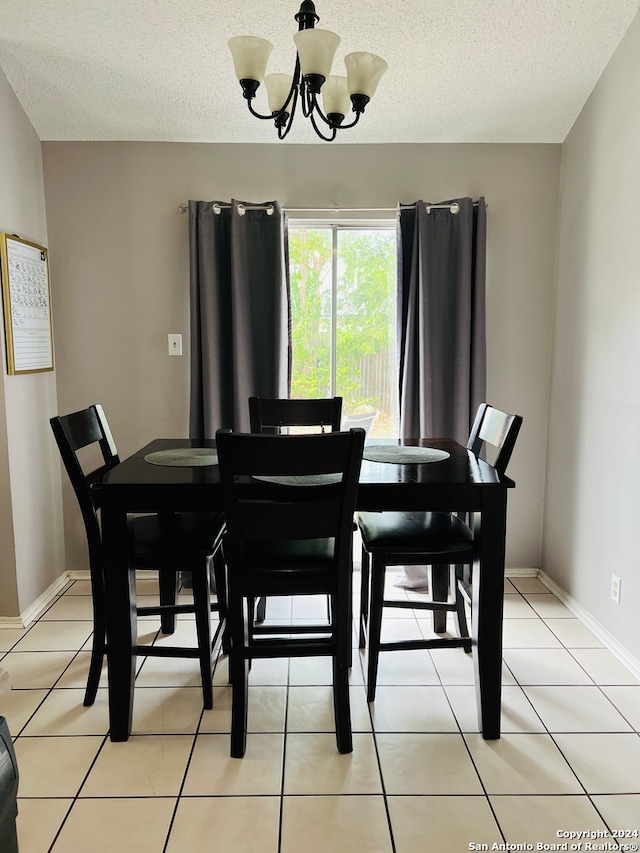 tiled dining space with a chandelier and a textured ceiling