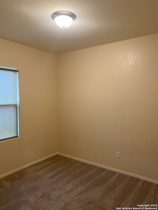 carpeted spare room featuring a textured ceiling