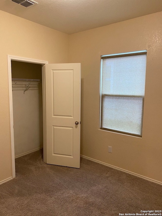 unfurnished bedroom featuring a closet and dark colored carpet