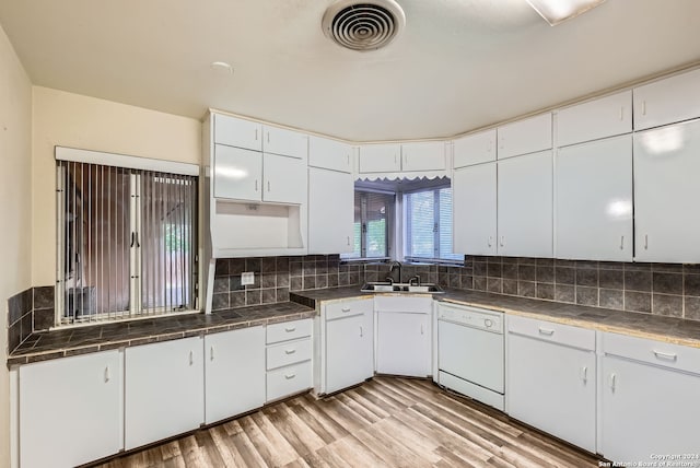 kitchen with white cabinetry, sink, tasteful backsplash, white dishwasher, and light hardwood / wood-style flooring