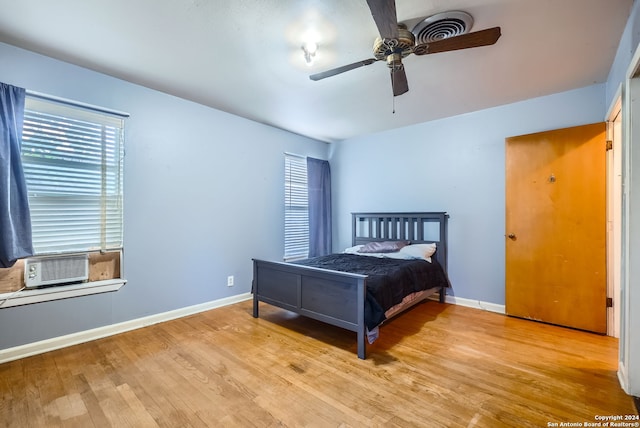 bedroom featuring light hardwood / wood-style flooring, cooling unit, and ceiling fan