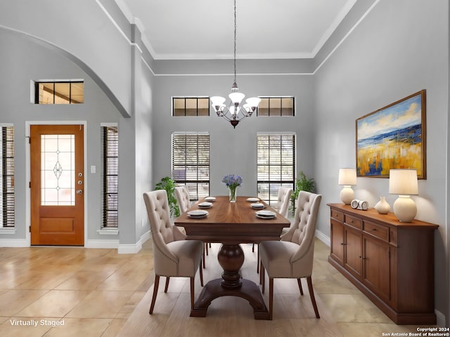 dining room featuring a towering ceiling, ornamental molding, light tile patterned flooring, and a notable chandelier