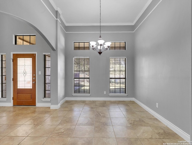 tiled foyer featuring a high ceiling, crown molding, and an inviting chandelier