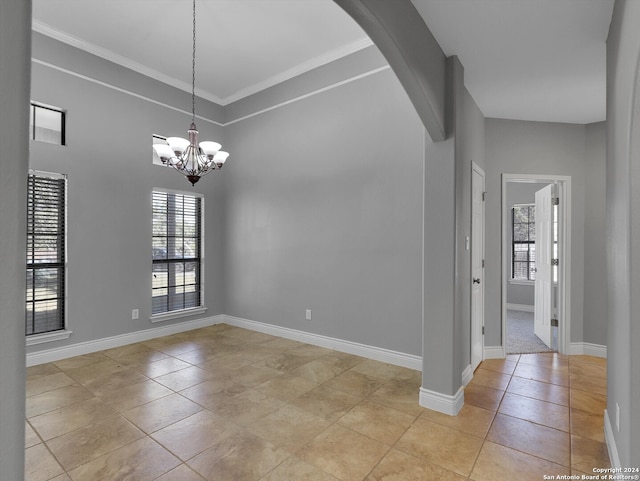 unfurnished room with a notable chandelier, light tile patterned floors, and crown molding