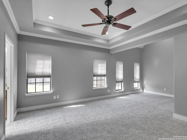 carpeted empty room with ceiling fan, crown molding, and a tray ceiling