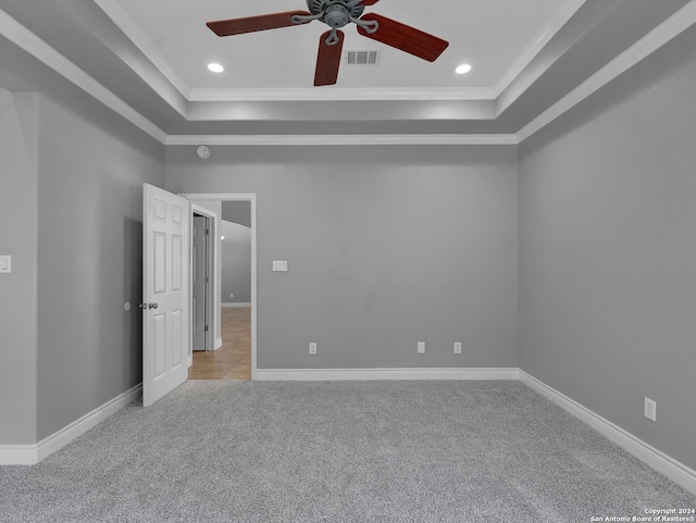 carpeted empty room featuring ceiling fan, a tray ceiling, and ornamental molding