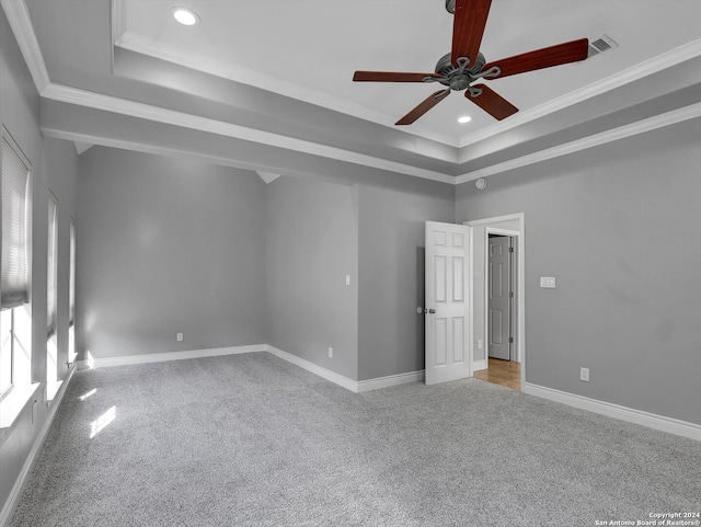 unfurnished room featuring ornamental molding, light carpet, ceiling fan, and a tray ceiling