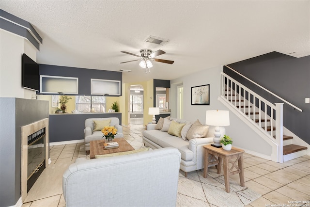 living room featuring a textured ceiling, light tile patterned floors, and ceiling fan