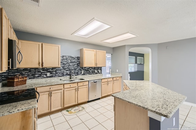 kitchen featuring light brown cabinets, backsplash, appliances with stainless steel finishes, and a center island