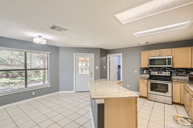 kitchen with stainless steel appliances, light stone counters, tasteful backsplash, and a kitchen island