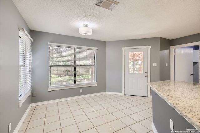 kitchen with light tile patterned flooring, a textured ceiling, and light stone countertops