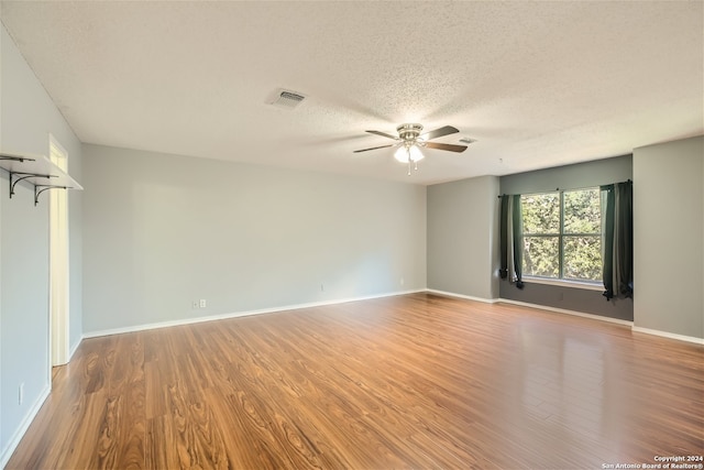 empty room with hardwood / wood-style floors, ceiling fan, and a textured ceiling