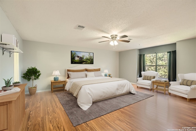 bedroom with a textured ceiling, hardwood / wood-style flooring, and ceiling fan