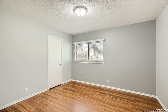 spare room featuring a textured ceiling and hardwood / wood-style flooring