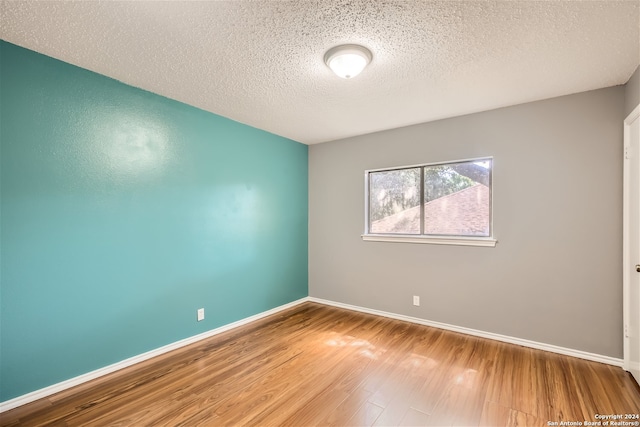 spare room featuring wood-type flooring and a textured ceiling