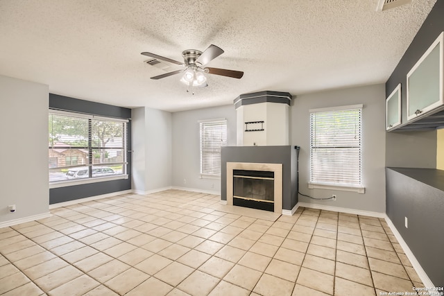 unfurnished living room with a textured ceiling, light tile patterned floors, and ceiling fan