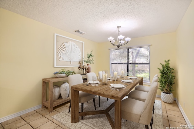 dining room featuring an inviting chandelier, a textured ceiling, and light tile patterned floors