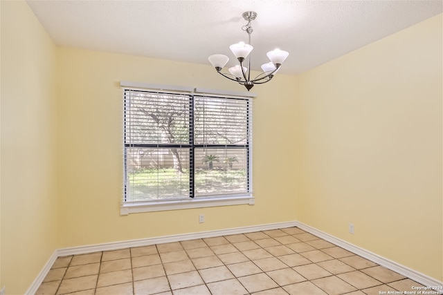 tiled spare room with a chandelier