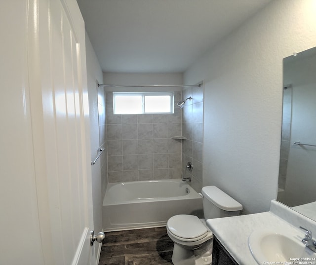 full bathroom featuring hardwood / wood-style floors, vanity, tiled shower / bath combo, and toilet