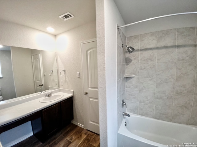 bathroom with hardwood / wood-style flooring, vanity, and tiled shower / bath combo