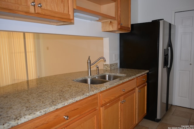 kitchen with light stone countertops, sink, light tile patterned floors, and stainless steel fridge with ice dispenser