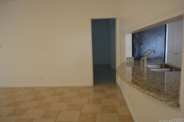 kitchen featuring sink, light stone counters, and light tile patterned floors