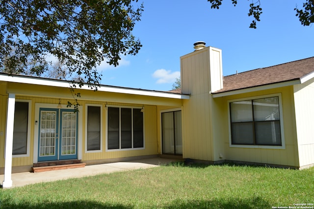 rear view of house featuring a lawn and a patio