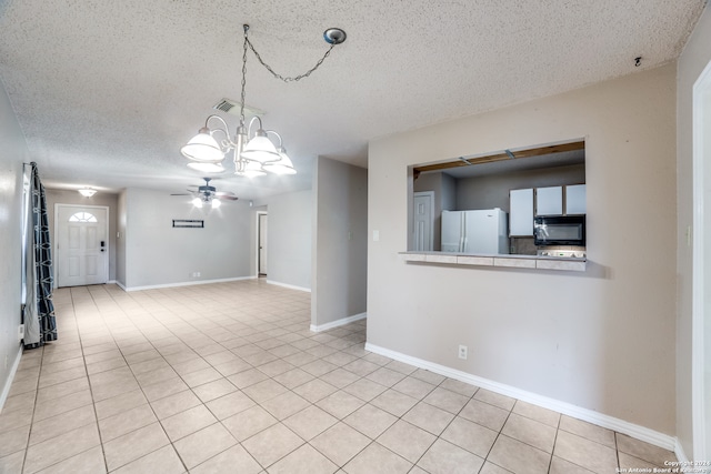 spare room featuring a textured ceiling, light tile patterned flooring, and ceiling fan with notable chandelier