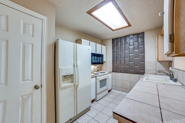 kitchen featuring tile countertops, a textured ceiling, sink, light tile patterned floors, and white appliances