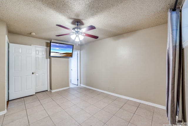 unfurnished bedroom featuring ceiling fan, a textured ceiling, light tile patterned floors, and a closet