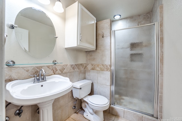 bathroom featuring toilet, tile walls, tile patterned floors, and a shower with shower door