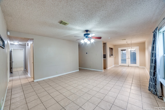 tiled spare room featuring french doors, ceiling fan with notable chandelier, and a textured ceiling