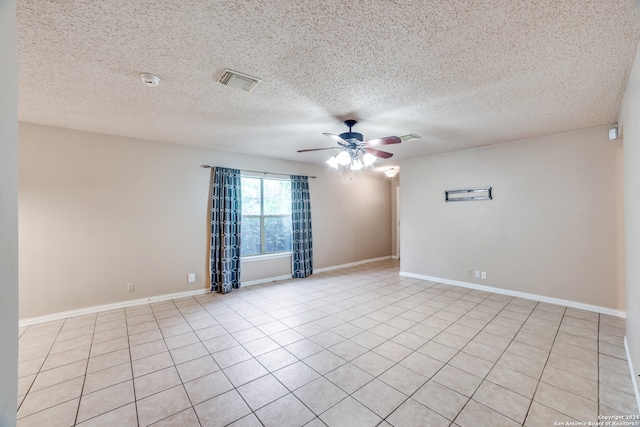 empty room featuring a textured ceiling, ceiling fan, and light tile patterned floors