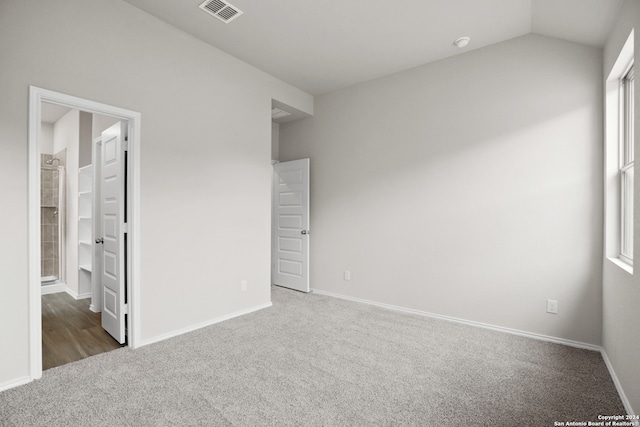 unfurnished bedroom featuring dark colored carpet and vaulted ceiling