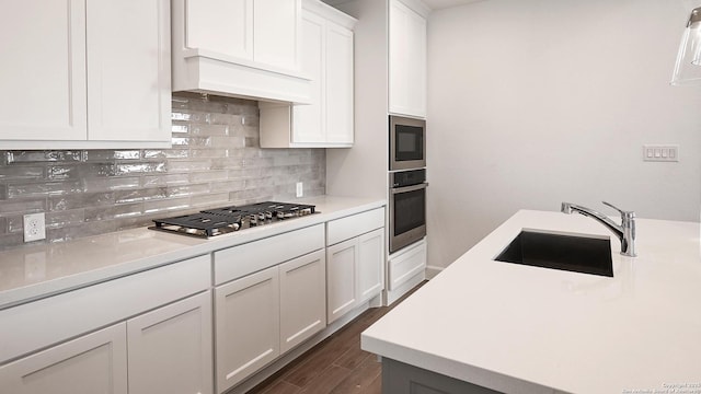 kitchen featuring stainless steel appliances, dark wood-style flooring, a sink, light countertops, and tasteful backsplash