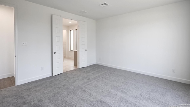 unfurnished bedroom with carpet floors, connected bathroom, visible vents, and baseboards