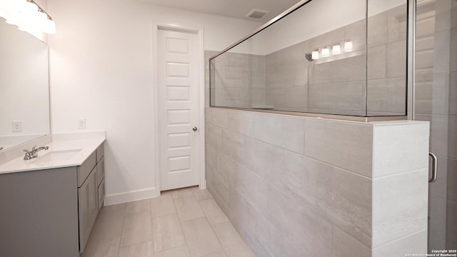 bathroom featuring baseboards, visible vents, tiled shower, and vanity