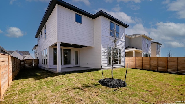 back of property with a fenced backyard, a patio, and a yard