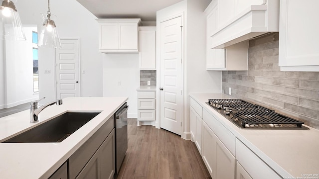 kitchen featuring custom exhaust hood, light countertops, appliances with stainless steel finishes, a sink, and wood finished floors