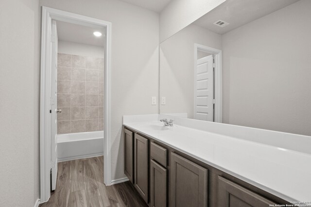 bathroom featuring hardwood / wood-style flooring, vanity, and tiled shower / bath combo