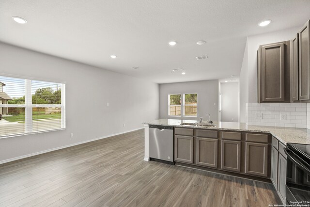 kitchen with dark wood-type flooring, stainless steel dishwasher, black range with electric stovetop, and sink